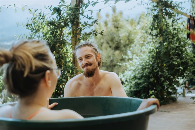 Franz lacht neben einer Teilnehmerin im Eisbad-Fass